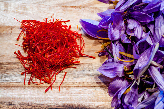 Red saffron threads and purple crocus flowers on a wooden board