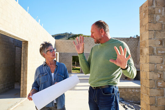 Architect and builder discussing blueprints at construction site