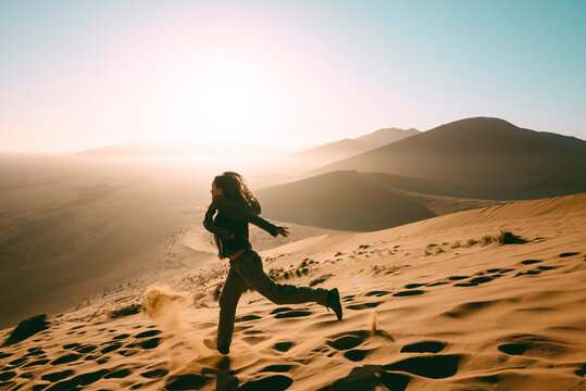 Namibia, Namib Desert, Sossusvlei, Woman running down the Dune 45 at sunrise