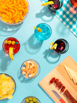 Blue table set with various snacks, appetizers and cocktails