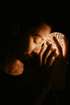 Woman meditating with a glowing orb in the dark