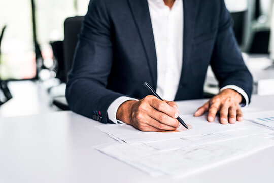 Close-up of businessman with documents at desk in office