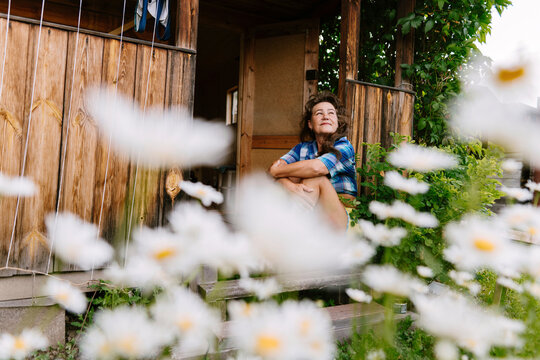 Smiling person relaxing on rustic wooden house porch in summer