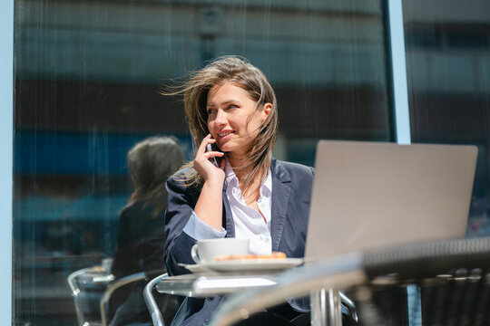 Smiling businesswoman calling on smartphone at an outdoor cafe