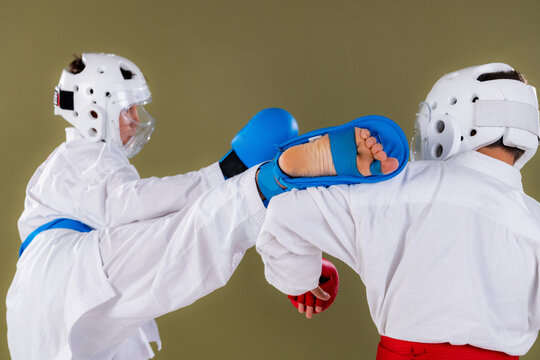 Karate athlete delivers a powerful high kick aimed at the opponent's upper body, intercepted and blocked at chest level by the defender  