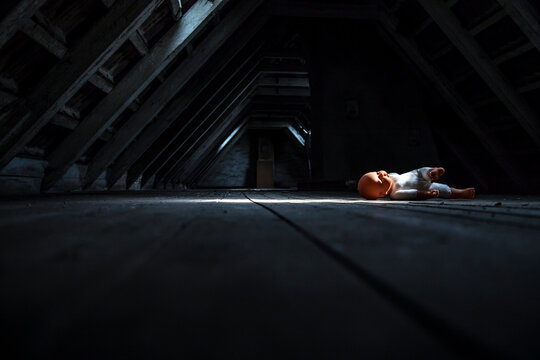 Doll lying at empty dark attic