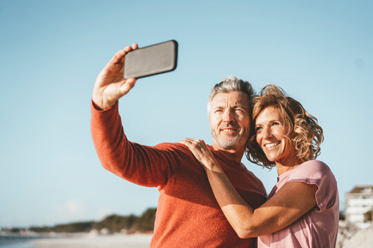 Smiling man taking selfie with woman through smart phone