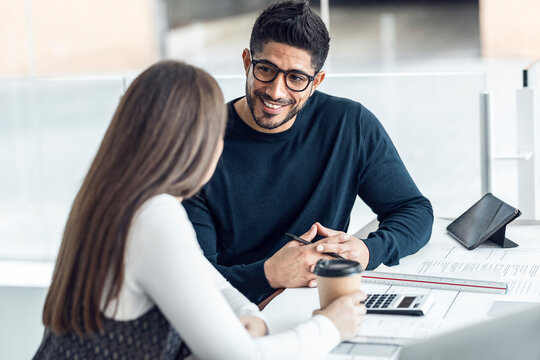 Happy businessman having discussion with colleague at desk in office