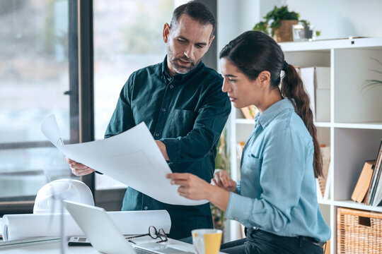 Architects discussing floor plan in small office