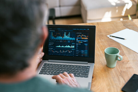 Broker analyzing financial charts on a laptop at a desk