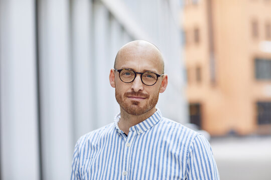 Confident mid adult man wearing striped shirt while standing on street