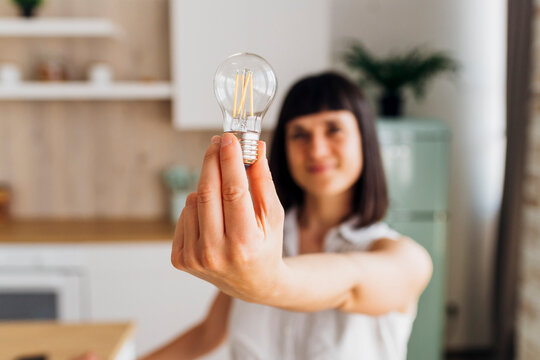 Woman holding light bulb at home