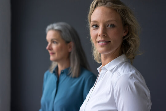Portrait of smiling young businesswoman with mature businesswoman in background
