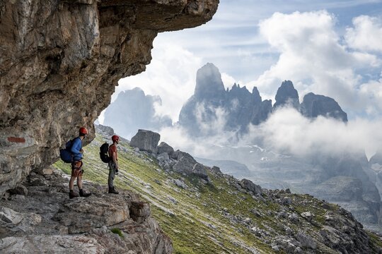 Two mountaineers on a path in front of a picturesque mountain landscape with rocky peaks, Via Ferrata SOSAT via ferrata, Cima Tosa summit in the back, Brenta Mountains, Trentino, Italy