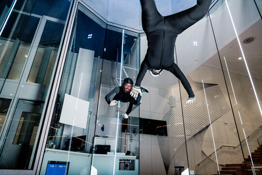 Smiling athlete with friend flying in wind tunnel