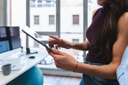 Coworker holding digital tablet and discussing business in office
