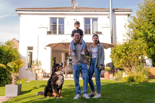 Family with dog enjoying time together in garden of modern home