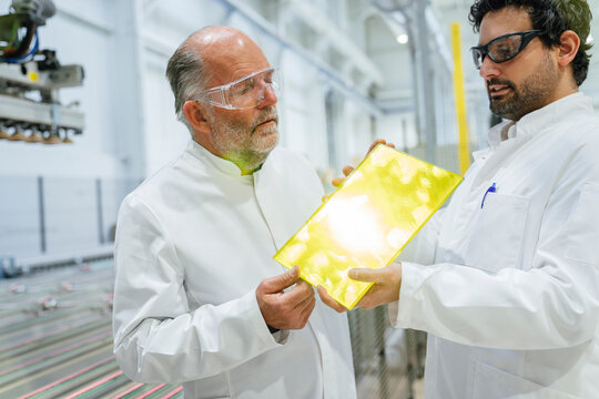 Scientists in a laboratory discussing a product with safety goggles and white coats