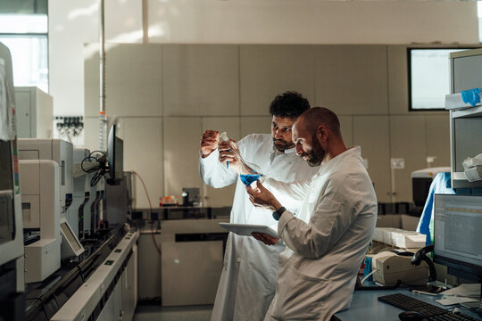 Scientist team evaluating liquid with tablet in medical laboratory