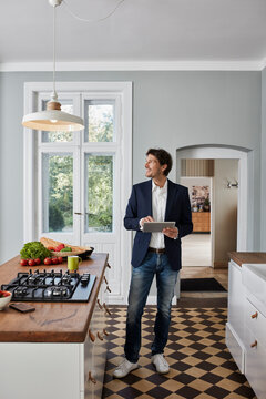 Man using tablet in kitchen looking at ceiling lamp
