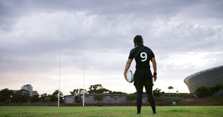 Rugby, thinking or man on field with ball, goal mindset or daydreaming in fitness hobby. Reflection, back or player outdoor with space, athlete insight or performance perspective in collision sport. © peopleimages.com