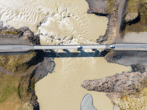 Aerial view of bridge over churning glacial river in Iceland