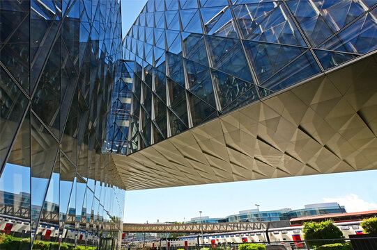 Geneva, Switzerland, Europe :  05.2026 : Japan International Tobacco headquarters building, Stadler trains in Geneve-Secheron station, pedestrian passage above rails leading to Maison de la Paix