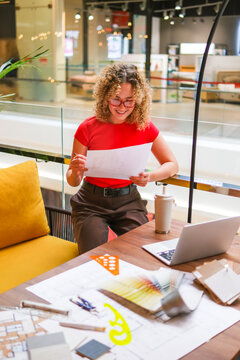 Smiling architect reviewing blueprints at a modern workspace desk