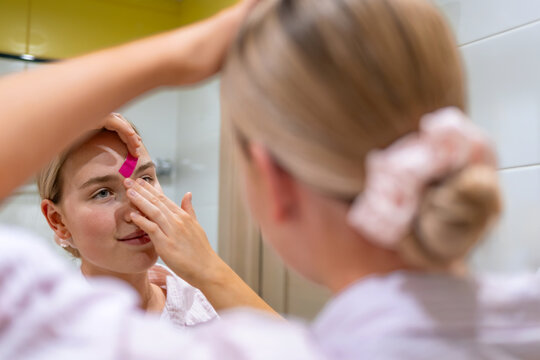 Face taping in bathroom mirror for anti aging skincare routine