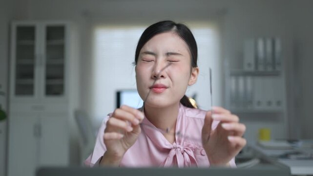 Overworked Asian businesswoman taking off her glasses and rubbing her tired eyes. Experiencing eye strain and fatigue from working late at night