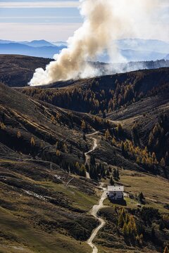 Rising smoke in autumnal landscape, in front the Merano Hut, Merano 2000 ski and hiking area, near Merano, South Tyrol, Italy