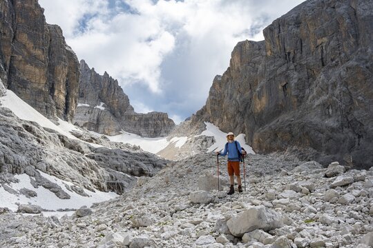 Hikers in a gap, Sentiero Brentari in front of rock faces, Brenta Mountains, Brenta-Adamello Natural Park, Trentino, Italy
