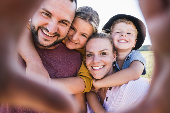 Laughing family embracing and looking through hands at camera