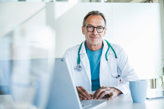 Smiling senior doctor sitting at desk
