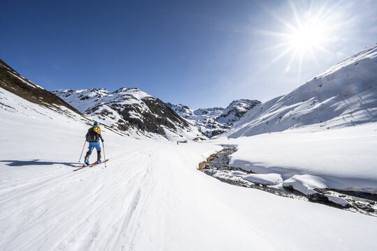 Ski tourer in the snow by a mountain stream in the Funtauna Valley, Sonnenstern, Graub&uuml;nden Haute Route, Albula Alps, Rhaetian Alps, Graub&uuml;nden, Switzerland