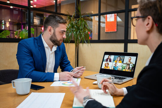Male and female professionals on video call during meeting in board room at office