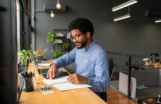 Businessman examining notes in diary near laptop at desk