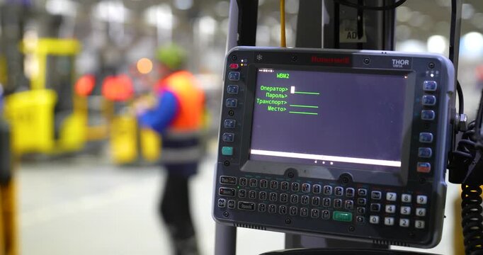 Steady close-up shot of a rugged vehicle-mounted computer terminal screen on a forklift displaying a login menu in a distribution center