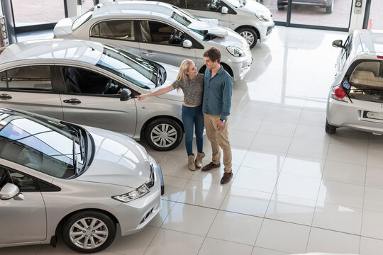 Young couple looking at new cars at car dealership
