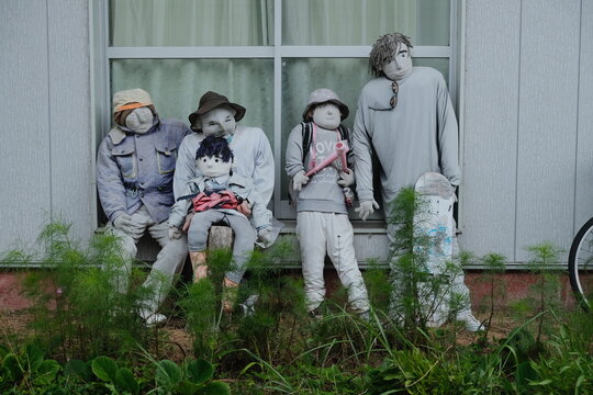 Rural Scarecrow Family Stands Among Greenery