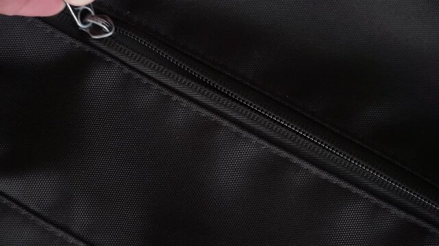 Person opening a backpack zipper to to put hand sanitizer into the bag. capturing modern lifestyle, mobile technology, and everyday activity