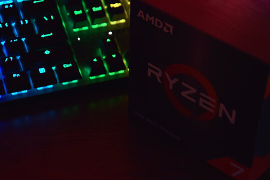 A close-up of an AMD Ryzen 7 5800X processor in a packaging box with backlit keyboards in the background.
