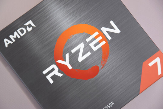 A close-up of an AMD Ryzen 7 5800X processor in a packaging box with backlit keyboards in the background.