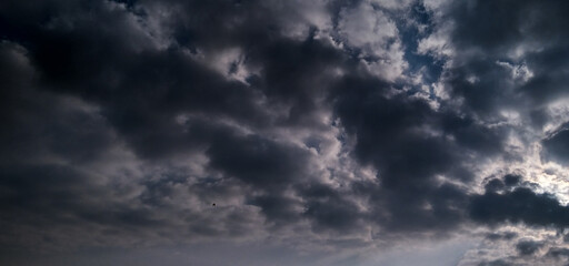 Obraz premium dramatic view of a cloudy sky filled with thick dark clouds and a subtle hint of hidden sunlight, creating a moody, pre-rain atmosphere