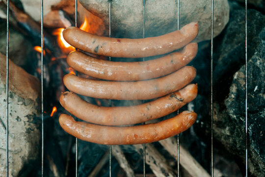 Sausages grilling on an open fire during a camping trip