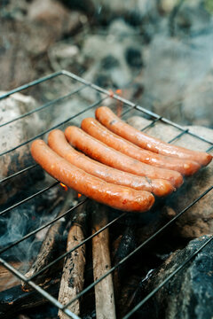 Sausages grilling on an open fire during a camping trip