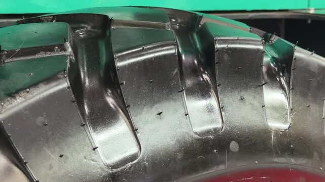 Close-up view of a rugged tire revealing intricate tread patterns and moisture on a construction vehicle's surface