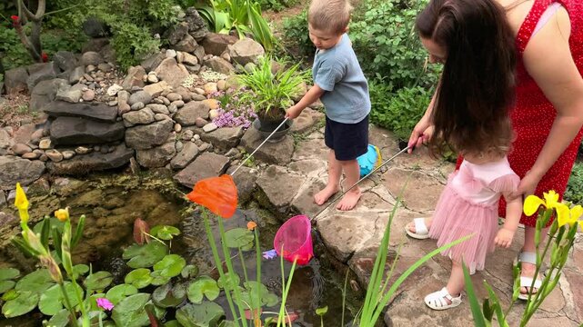 Children catching pond life in backyard garden with nets during nature exploration.