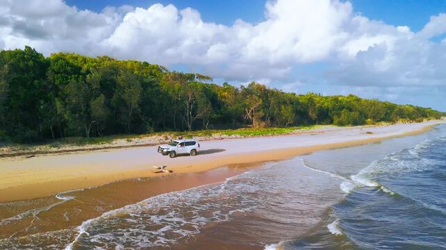 Aerial Drone Shot of 4WD Vehicle on Fraser Island Pristine Beach With Lush Rainforest