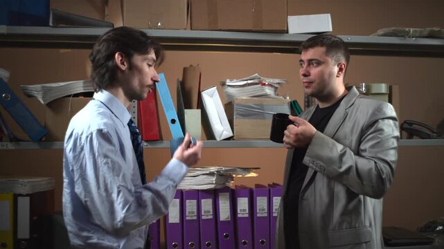 Two office workers reviewing documents in a storage room